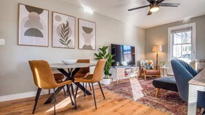 Ein modernes Wohnzimmer mit Essbereich, Deckenventilator und Kunstwerken an der Wand.