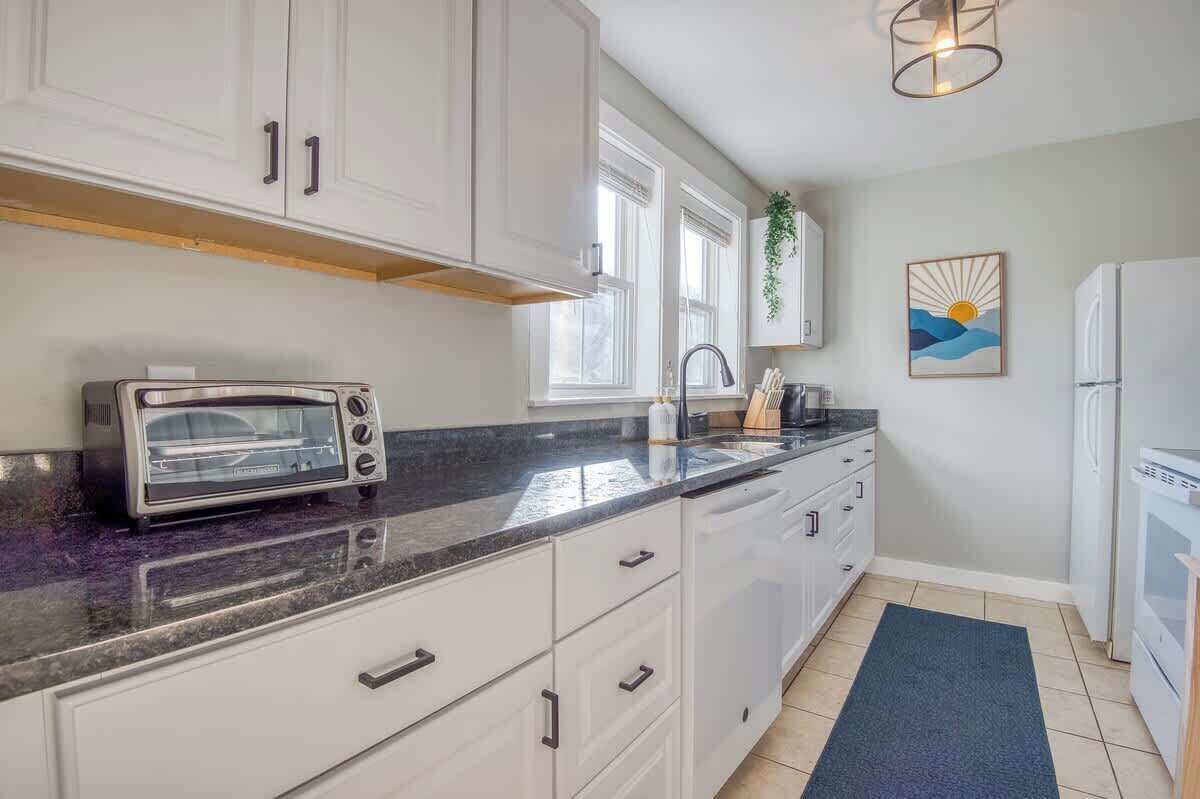 A kitchen with white cabinets, a toaster, a sink, and a refrigerator.