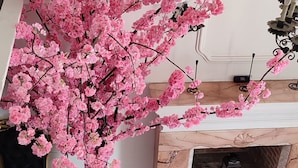 A cozy seating area with a marble fireplace, a pink flowering plant, and a small table with a vase. - T-hotel 4, Antigua Guatemala (Antigua Guatemala)