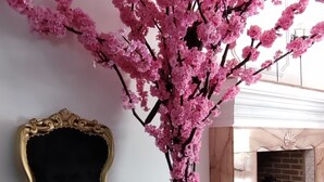 A black velvet chair with gold trim, a large vase with pink flowers, and a marble fireplace. - T-hotel 4, Antigua Guatemala (Antigua Guatemala)