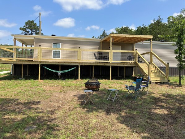 Une maison à deux étages avec une terrasse, un hamac et un barbecue.
