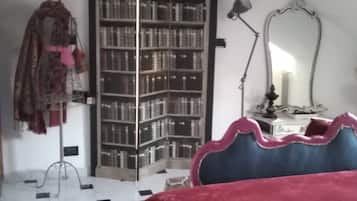 Une chambre à coucher avec un lit, une bibliothèque, un miroir et une lampe.