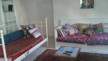 Una habitación con cama, sofá, una mesita y un cuadro colgado en la pared.