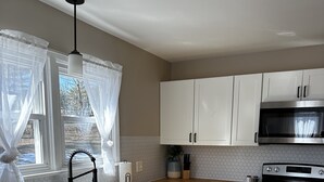 A modern kitchen with white cabinets, a stainless steel oven, and a wooden countertop. - Modern Country Farmhouse, Walking Distance to Lake (Averill Park)