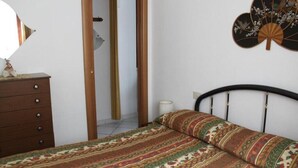 A bedroom with a bed, a dresser, a mirror, and a wall fan. - Casa Miclara apartment -- Agave (Zanca)