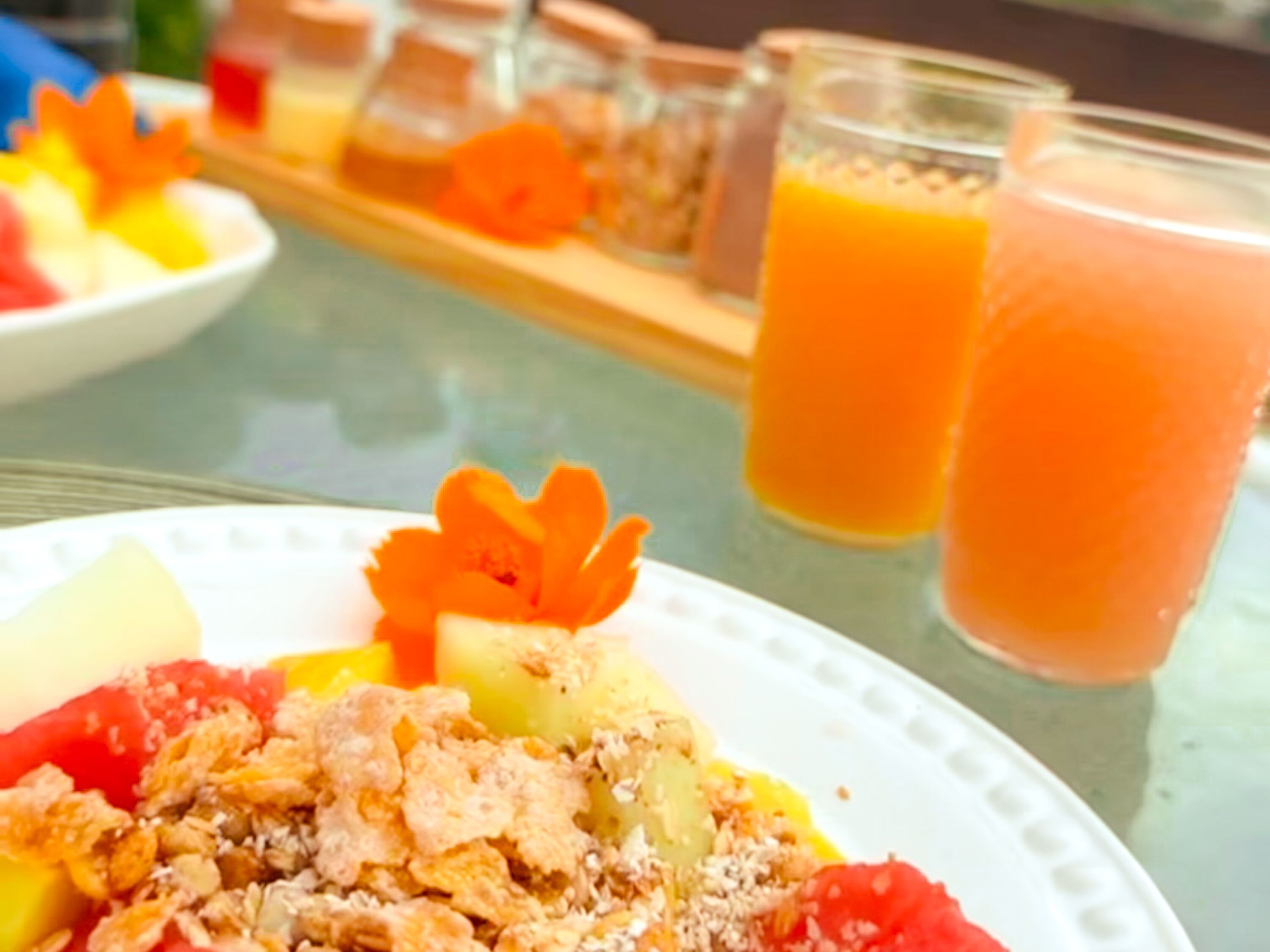 Ein Frühstücksbuffet mit verschiedenen Früchten, Müsli und Orangensaft.