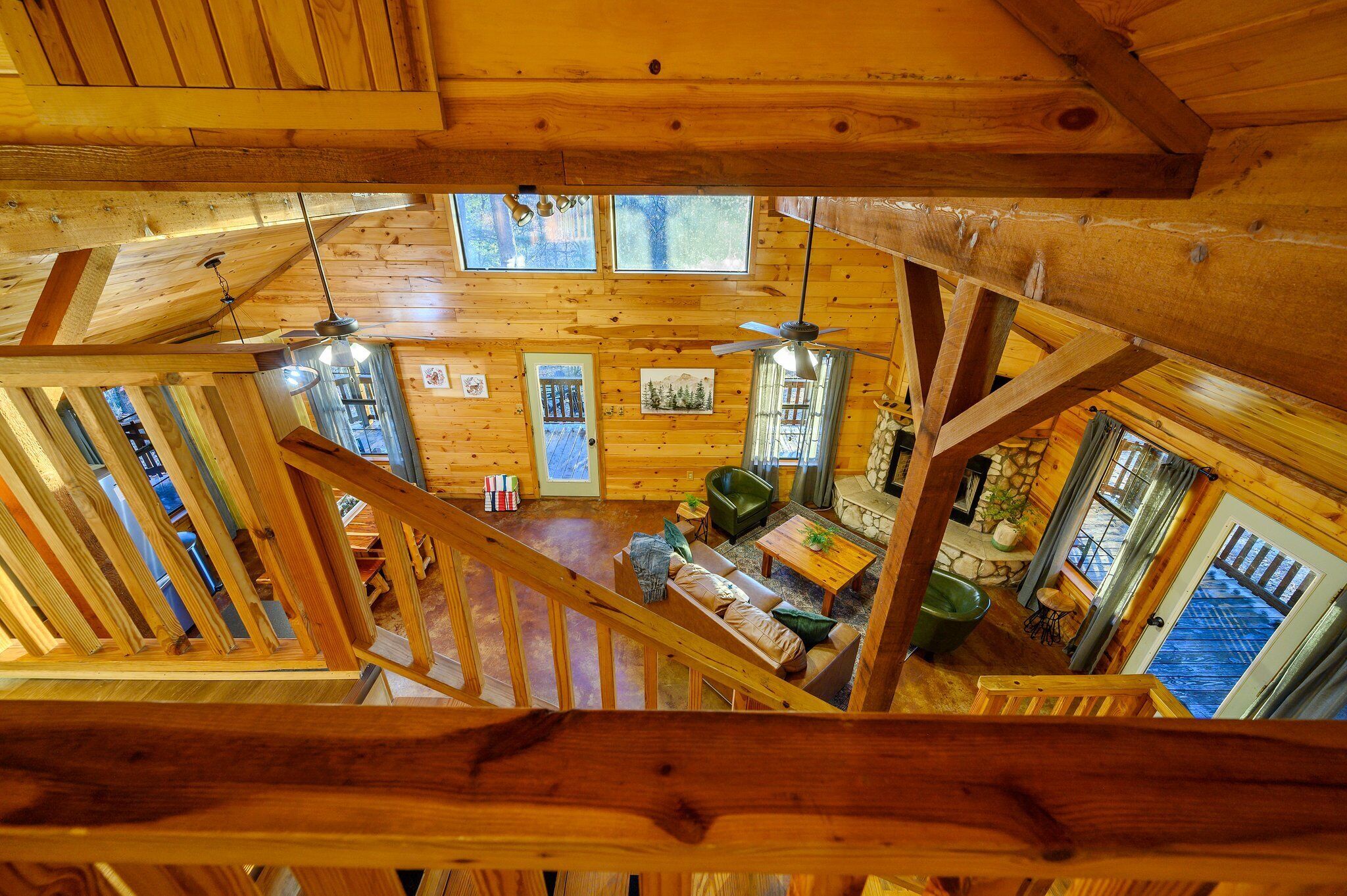 A wooden cabin interior with a loft bedroom, a dining area, and a kitchen.