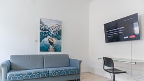 Ein modernes Wohnzimmer mit einer Couch, einem Glastisch und einem Wand-Fernseher, der einen Netflix-Begrüßungsbildschirm zeigt.