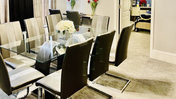 Un espace repas moderne avec une table en verre, des chaises en cuir et un luminaire contemporain.