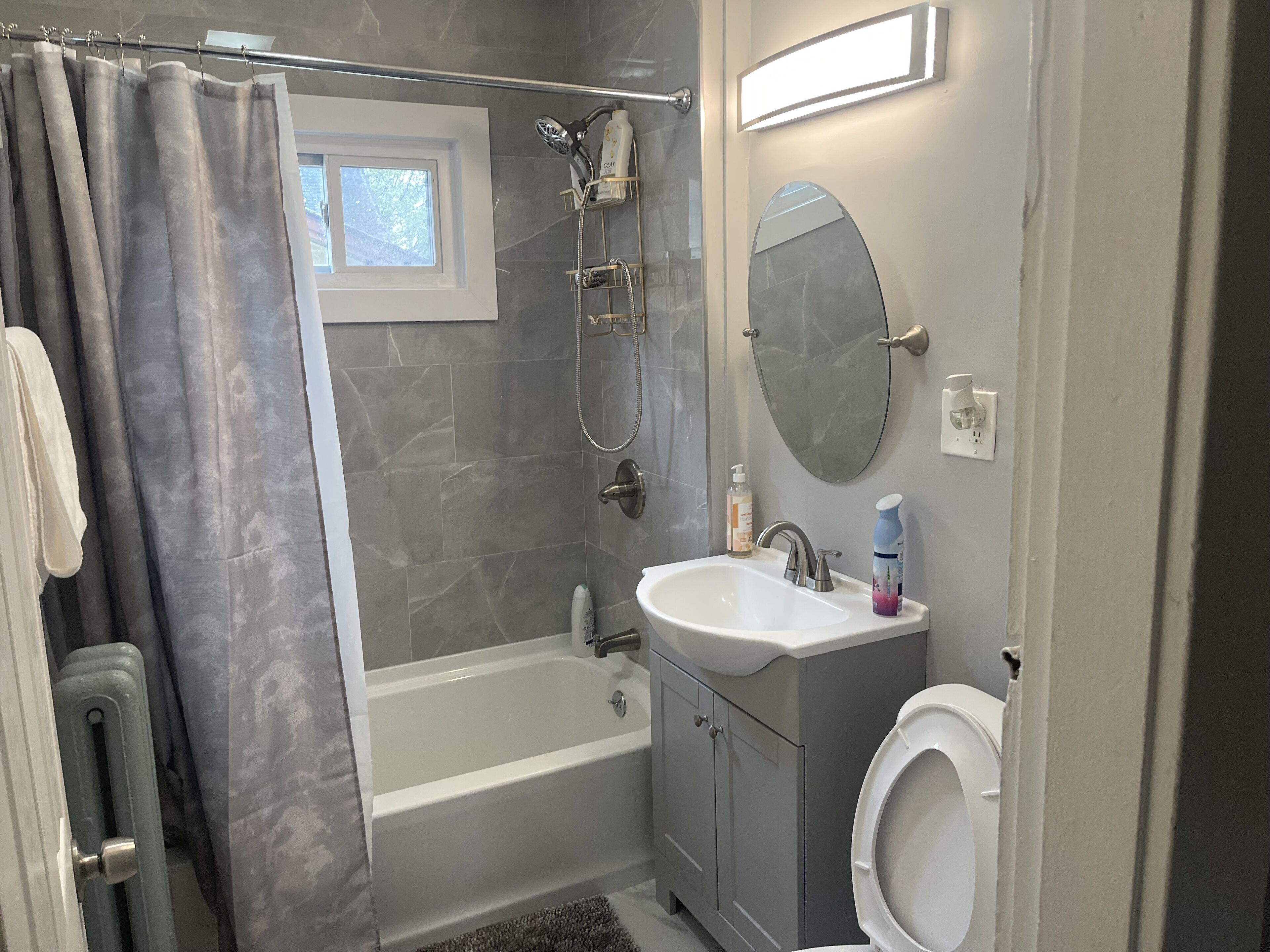 Et badeværelse med bruser, vask og toilet.