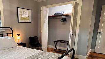 Een slaapkamer met een bed, een stoel, een kledingkast en een ingelijst kunstwerk aan de muur.