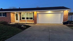 Een tweelaags huis met garage, oprit en een verzorgd gazon.