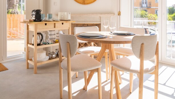 A dining area with a round table, chairs, and a coffee station. - Chalet Maria da Assunção T1 (Cascais)