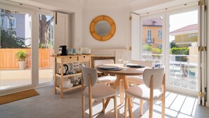 A dining area with a round table, chairs, and a buffet counter. - Chalet Maria da Assunção T1 (Cascais)