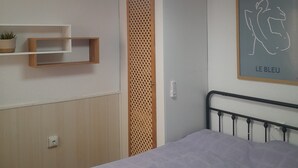 A bedroom with a bed, a wall-mounted shelf, a framed artwork, a ceiling light fixture, and a wooden panel divider. - Hogar del Corazon - 1st line on the lake - Pets welcome! (Torrevieja)