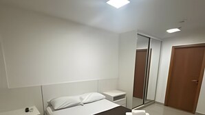 A modern hotel room with a bed, bedside tables, a mirror, and a wardrobe. - Brisas do Lago - apt 13 (Brasília)