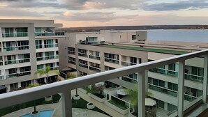 A modern hotel with multiple floors, a rooftop pool, and a view of a body of water. - Brisas do Lago - apt 13 (Brasília)