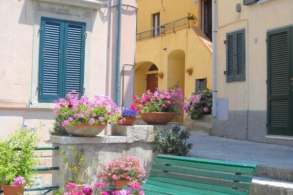 A building with a balcony, potted plants, and a green bench.