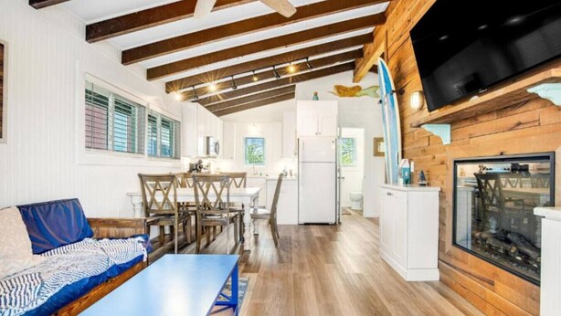 A spacious living area with a sofa, dining table, and kitchen in the background.