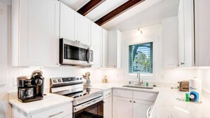 A modern kitchen with white cabinetry, a built-in oven, a microwave, and a window providing natural light.