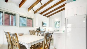 A modern kitchen with white cabinetry, a central island, and wooden chairs.