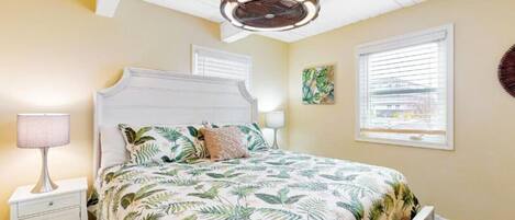 A bedroom with a bed, nightstands, a ceiling fan, and a window with blinds.