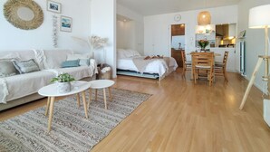 A modern, well-lit living room with a sofa, coffee table, and dining area.