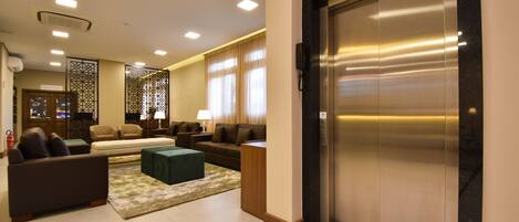 A modern hotel lobby with a sofa set, a coffee table, and an elevator.