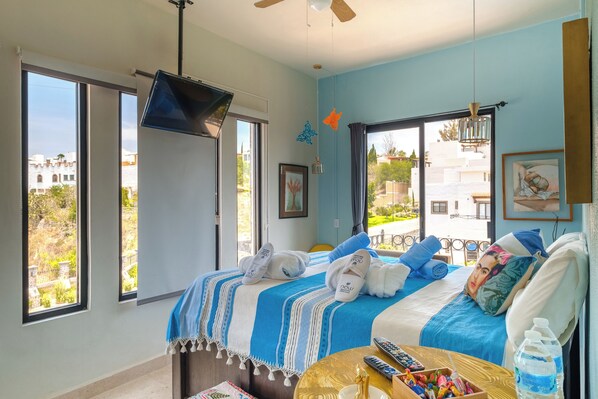 A hotel room with a bed, a TV, a balcony, and a view of buildings. - Casa Itzae ​La Antigua Dog Friendly (San Miguel de Allende)