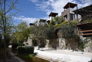 A stone building with a stone bridge, a small water channel, and outdoor seating areas. - Casa Itzae ​La Antigua Dog Friendly (San Miguel de Allende)