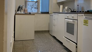 A compact kitchen with white cabinets, a built-in oven, and a window with a view. - Peking (Hannover)