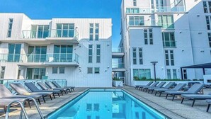 A pool deck with a modern building in the background. - Dual Master Bedroom Penthouse in Marina Del Rey, CA (Marina del Rey)