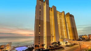 Een hoog hotel met meerdere verdiepingen, een zwembad en uitzicht op de oceaan.