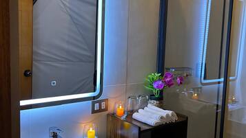 A modern bathroom with a large mirror, a white sink, and a glass shower enclosure.