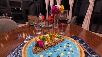 A dining table with a blue dessert, a glass of water, and a glass of red wine.