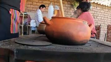 A person cooking on a traditional stove with a clay pot.