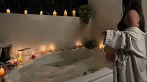 A woman in a robe by a bathtub with candles and glasses. - Miski Samay Domo Boutique (Urubamba)