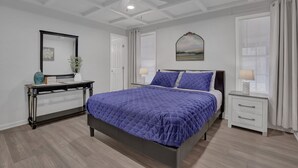 A bedroom with a bed, bedside tables, a desk, and a ceiling fan.