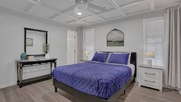 Un dormitorio con cama, mesitas de noche, un escritorio y un ventilador de techo.