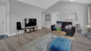 A modern living room with a flat-screen TV, a sofa, a coffee table, and a rug.