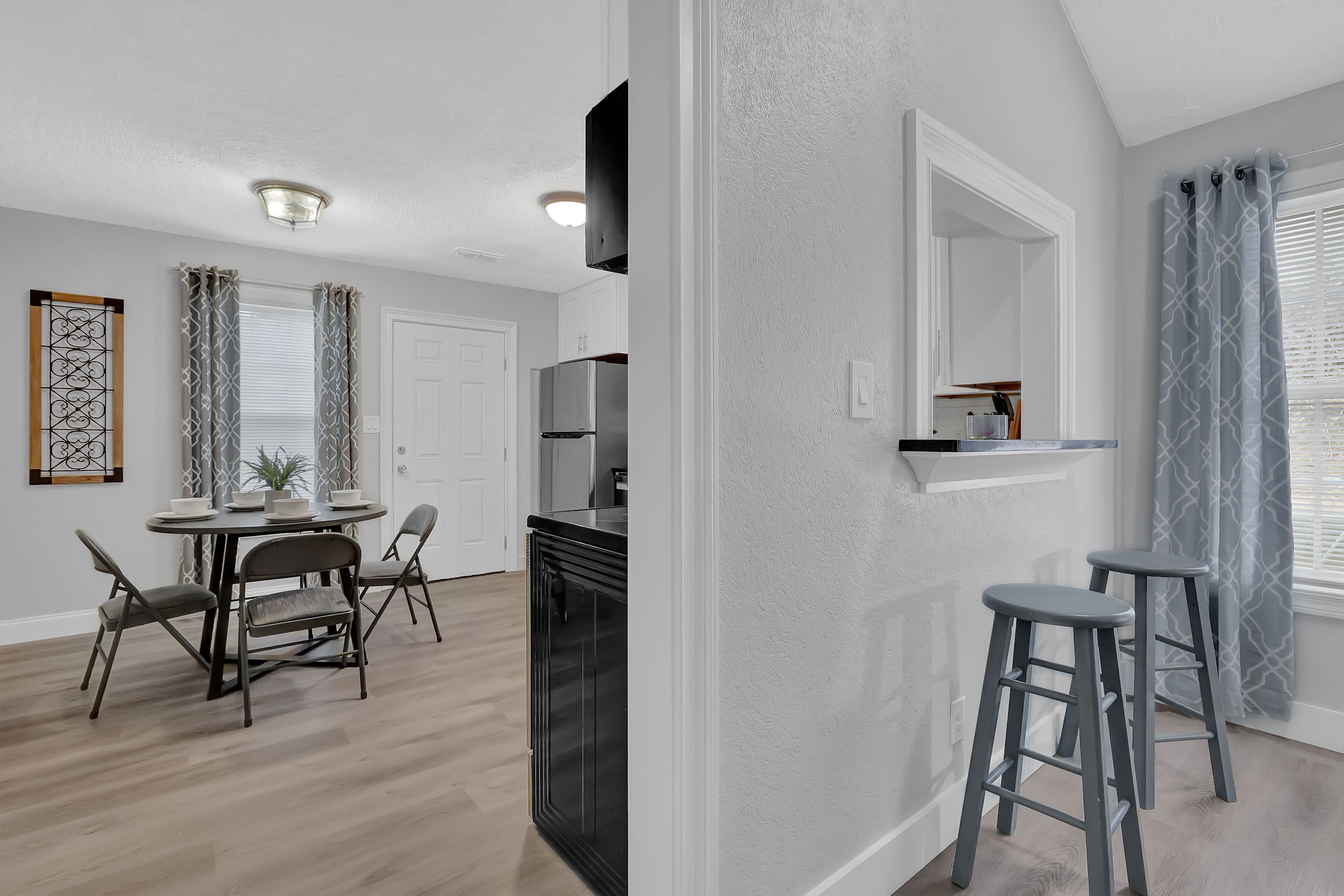 Una cocina moderna con un refrigerador empotrado, un comedor con una mesa redonda y sillas, y una barra con taburetes.