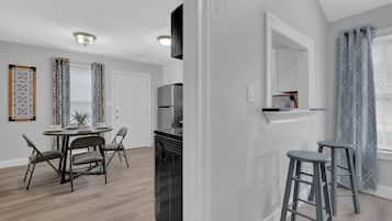 Una cocina moderna con un refrigerador empotrado, un comedor con una mesa redonda y sillas, y una barra con taburetes.
