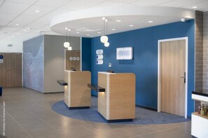 A reception area with two wooden reception desks, a blue wall, a map, and a door.