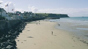 A beach with a rocky shoreline, a promenade with buildings, and a clear sky. - Holiday Inn Express Caen Epron by IHG (Epron)