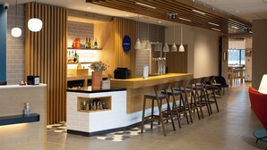 A modern bar area with a wooden counter, bar stools, and pendant lighting. - Holiday Inn Express Caen Epron by IHG (Epron)