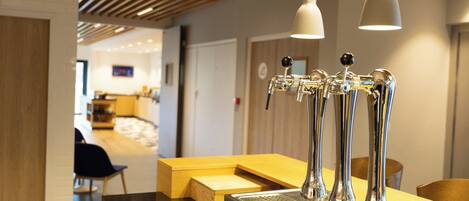 A modern bar area with stainless steel taps, a wooden counter, and pendant lighting.