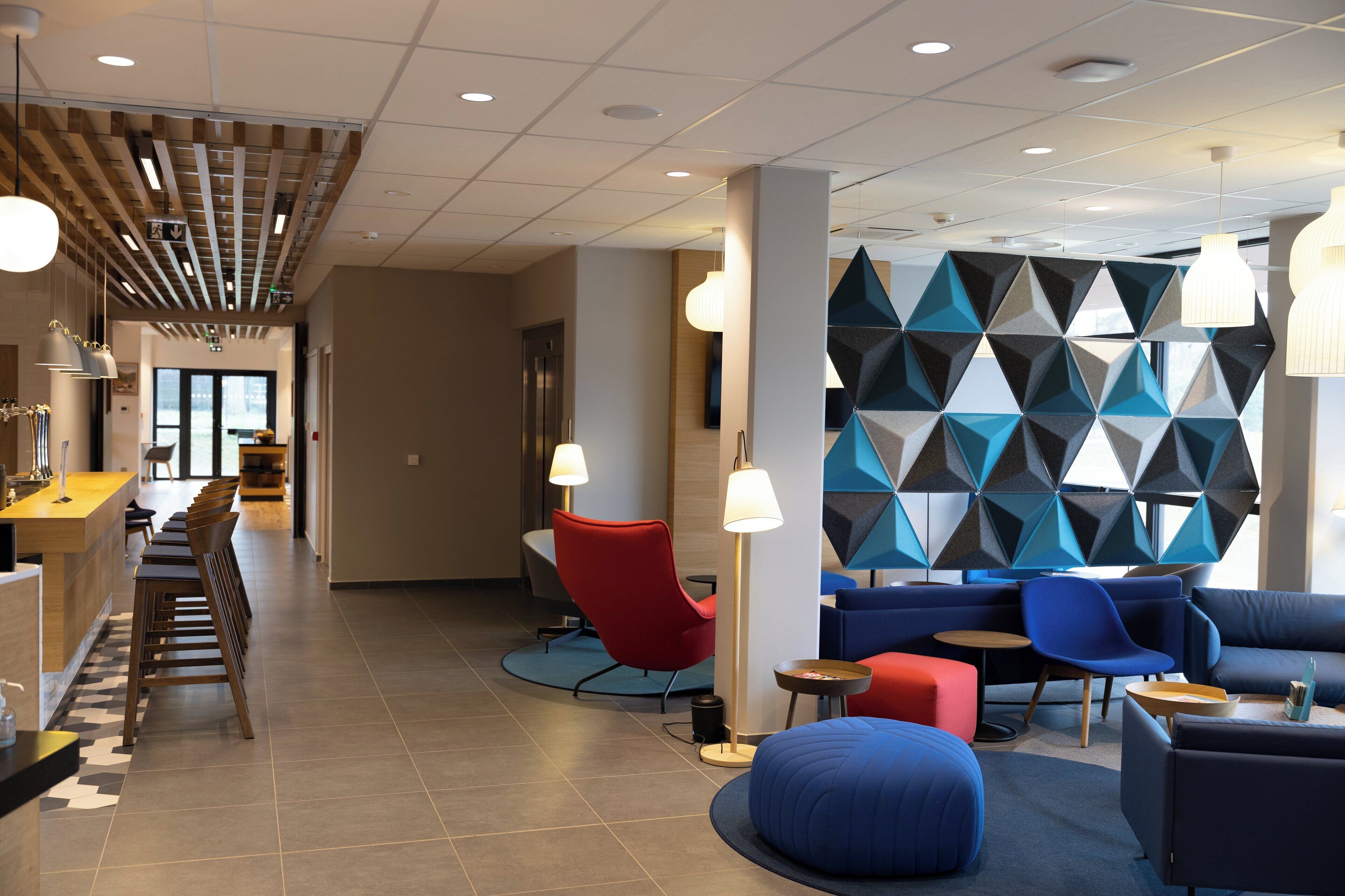 Um lobby moderno com área de bar, espaços de estar e um design de parede geométrico.