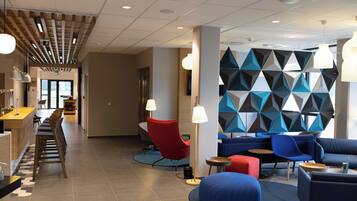 Un vestíbulo moderno con zona de bar, disposición de asientos y diseño de pared geométrico.