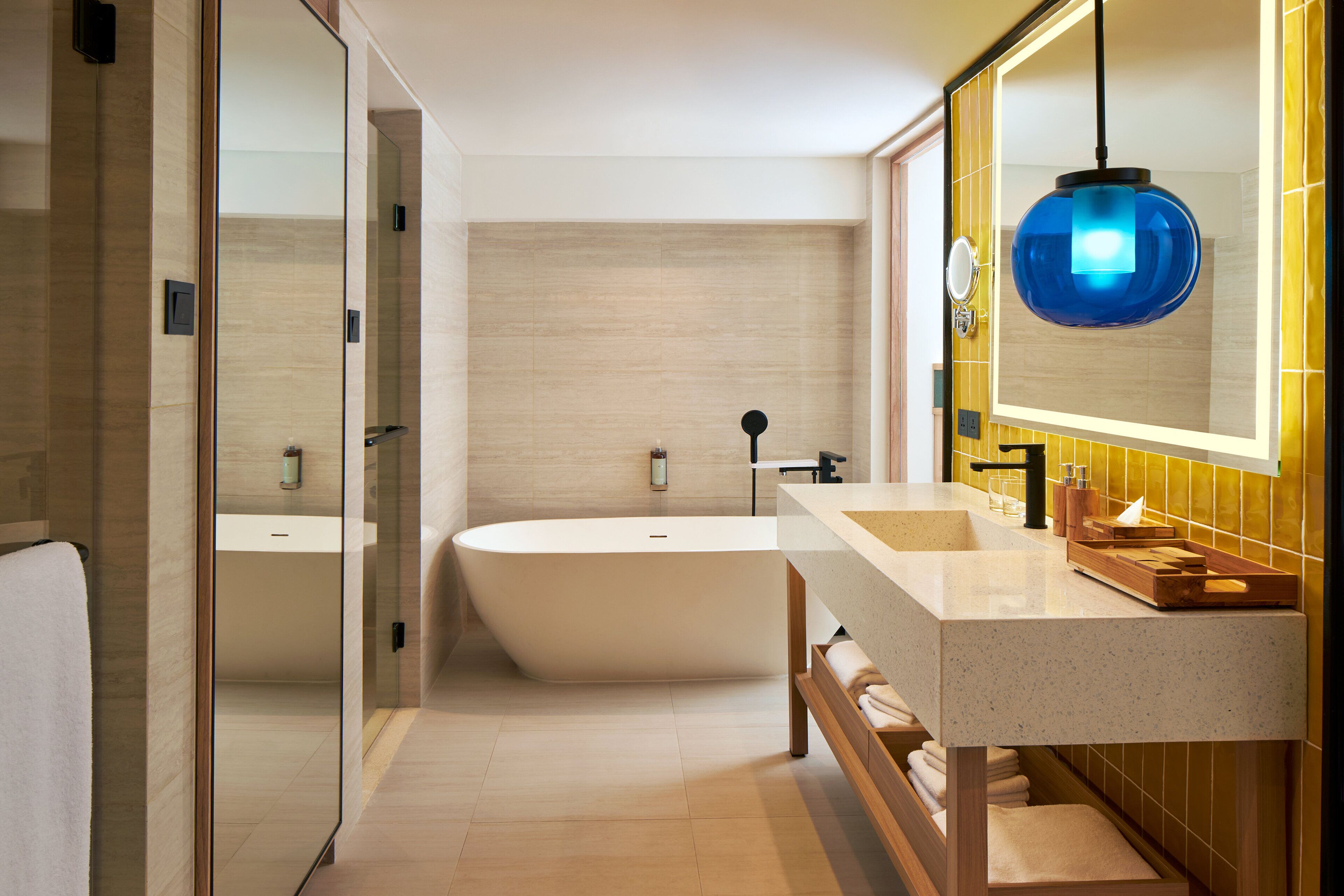 A modern bathroom with a freestanding bathtub, a large mirror, and a wooden vanity with a sink.