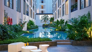 A modern hotel courtyard with a central pool, surrounded by lush greenery and seating areas. - voco Bali Seminyak by IHG (Keroboken Kelod)